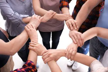 Une femme souriante animant un atelier de développement personnel avec un groupe de femmes concentrées et engagées à Shreveport.